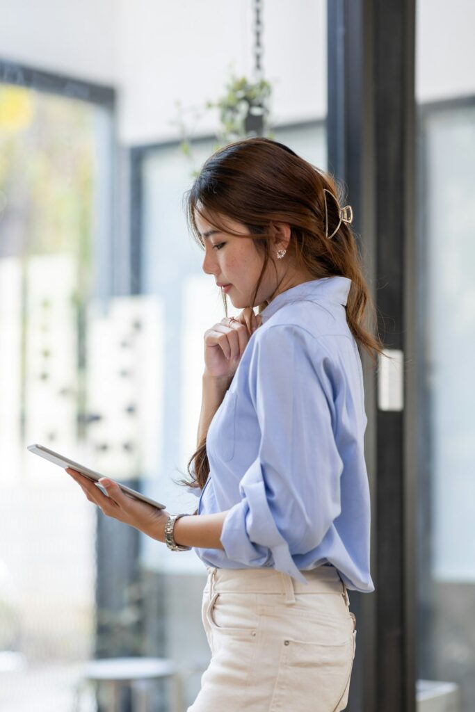 Young business Asian woman using tablet and standing near the window in workplace "